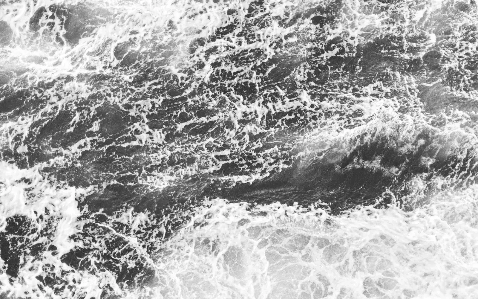 白い波が砕ける海面を真上から捉えた抽象的な風景